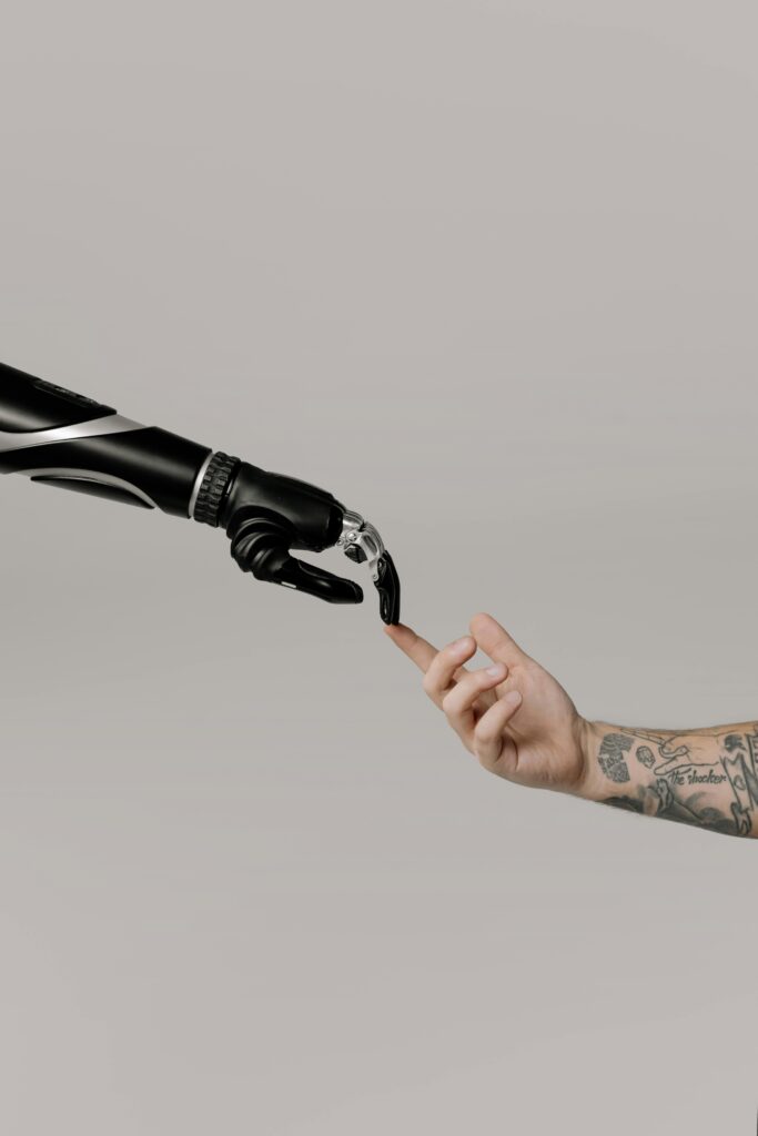 pexels-photo-6153345-6153345-1 Close-up of a prosthetic arm and a human hand reaching towards each other in harmony.